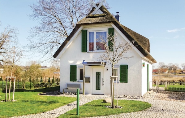 A white house with green shutters, a thatched roof, and a small porch. - Beautiful home in Insel Poel/Kirchdorf (Insel Poel/Kirchdorf)
