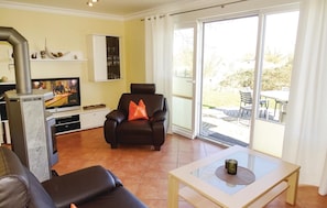 A living room with a fireplace, a television, a sofa, a chair, and a table. - Beautiful home in Insel Poel/Kirchdorf (Insel Poel/Kirchdorf)