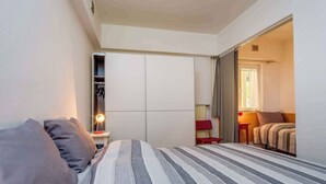 Quarto com cama, guarda-roupa e espelho.