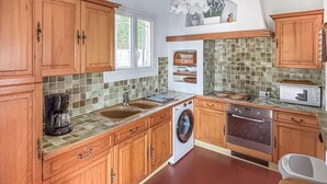 Eine Küche mit Holzausstattung, einem Geschirrspüler, einem Backofen und einer gefliesten Spritzschutzwand.