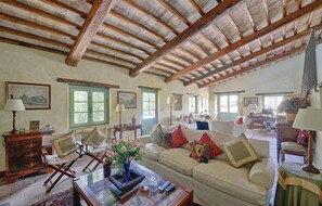 A spacious living room with a high wooden ceiling, a beige sofa, and a coffee table with decorative items. - Stunning home in Lugnano in Teverina (Lugnano in Teverina)