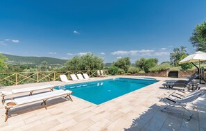 Ein rechteckiger Pool mit Holzterrasse und Liegestühlen.