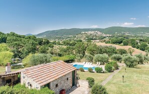 A stone building with a tiled roof, a swimming pool, and a view of a village in the background. - Stunning home in Lugnano in Teverina (Lugnano in Teverina)