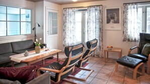 A cozy living room with a sofa, a wooden table, and two rocking chairs. - Stunning home in Dølemo with sauna (Dølemo)
