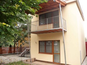 A two-story building with a balcony, a wooden staircase, and a large window. - Holiday apartment with modern furnishings only 120 m from the beach (Siófok)