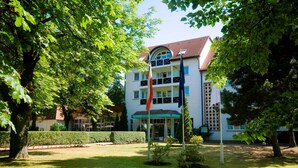 Un hôtel doté d’une entrée centrale, entouré de pelouses et d’arbres bien entretenus.
