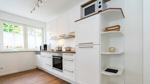 A modern kitchen with white cabinetry, a built-in oven, and a microwave.
