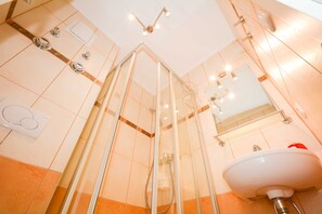 Un bagno moderno con cabina doccia in vetro, un lavandino bianco e uno specchio.