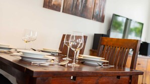 A dining table set with plates, glasses, and cutlery, with chairs around it.