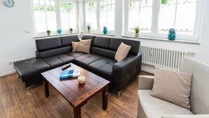 A modern living room with a sectional sofa, a wooden coffee table, and a beige armchair.