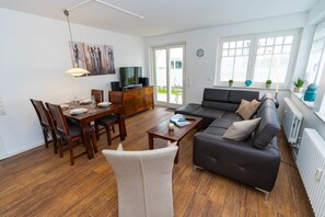 A modern living room with a dining area, a sofa, and a TV.