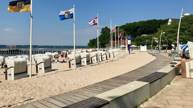 En strand med en træpromenade, strandstole og flag.