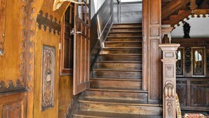 Eine hölzerne Treppe mit aufwendigen Schnitzereien und einem dekorativen Geweih an der Wand.