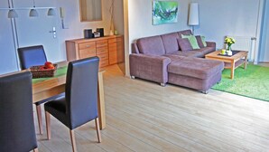 Una sala de estar moderna con un sofá, una mesa de comedor con sillas, una mesita auxiliar y un radiador.