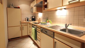 Una cocina moderna con armarios de madera, un lavamanos de acero inoxidable y un lavavajillas.