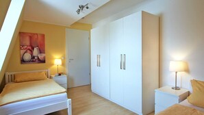Un dormitorio con cama, mesitas de noche, un armario y un cuadro en la pared.