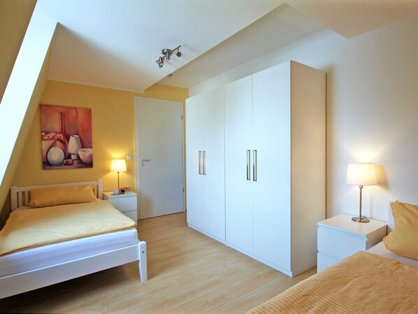 A bedroom with a bed, nightstands, a wardrobe, and a painting on the wall.