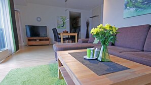 Una sala de estar moderna con una mesa de centro de madera, un sofá, un televisor y un comedor con sillas y una mesa.