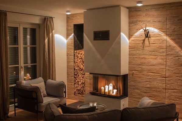 A cozy living room with a fireplace, comfortable seating, and a stone wall.