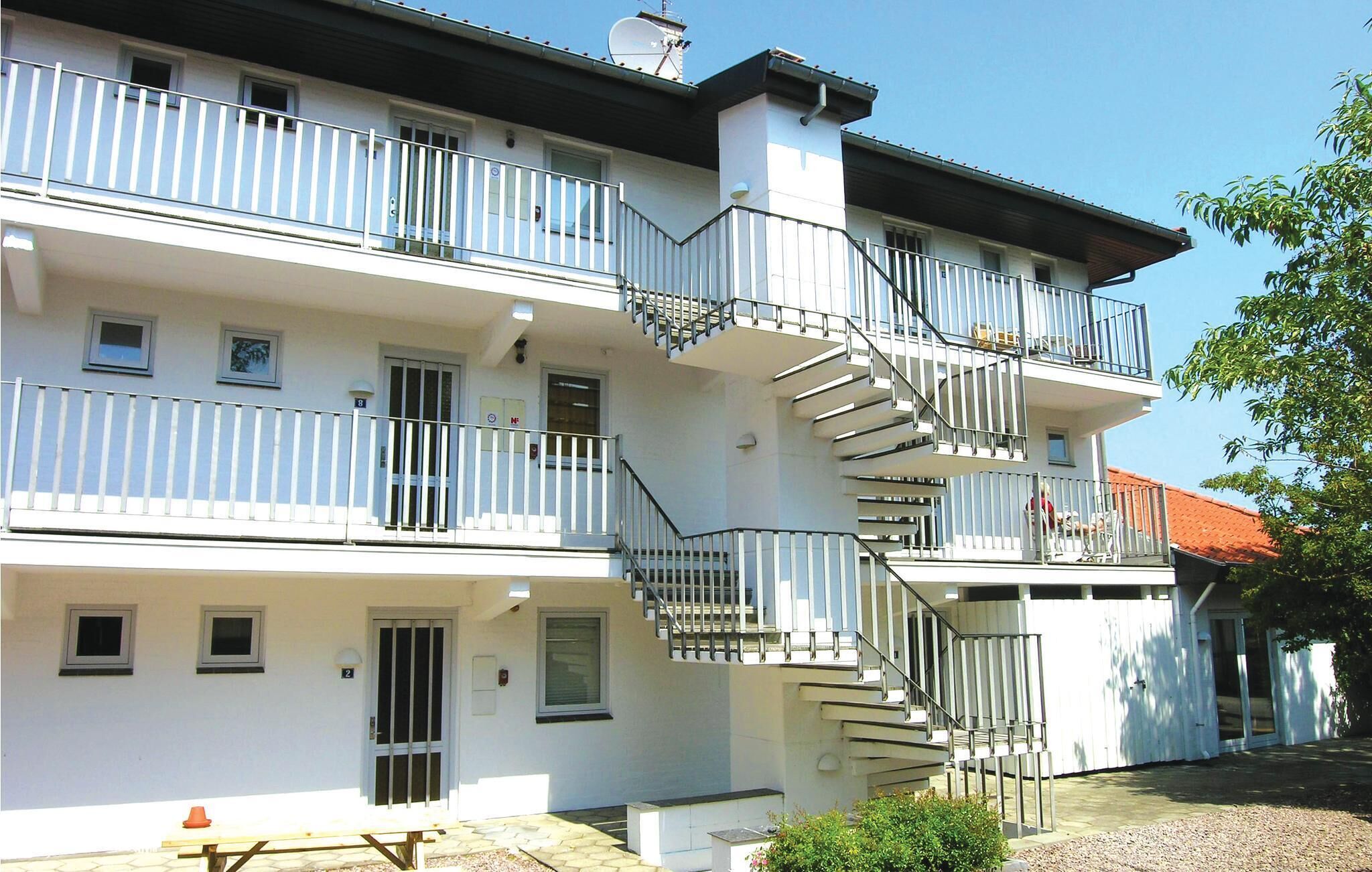 A multi-story residential building with balconies, a staircase, and a small outdoor seating area.