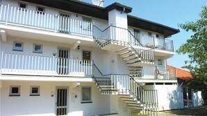 Un edificio residenziale a più piani con balconi, una scala e un piccolo spazio esterno con posti a sedere.