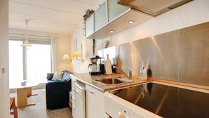 Una cucina moderna con una cappa aspirante in acciaio inossidabile, un forno a incasso e un lavello. È presente una zona pranzo con tavolo e sedie.