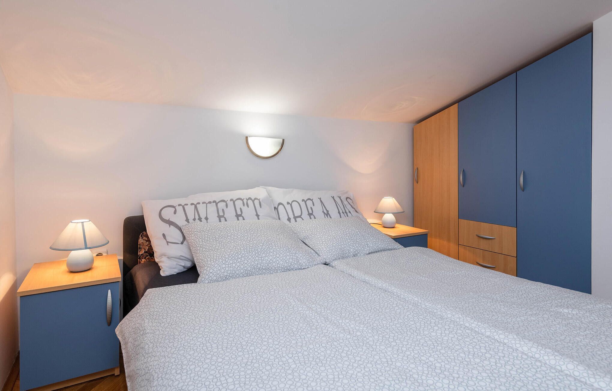 Een slaapkamer met een bed, twee nachtkastjes, een kledingkast en een wandlamp.