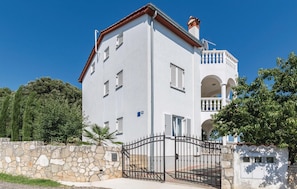 Un edificio su due piani con un muro in pietra, un cancello e un balcone con ringhiera.