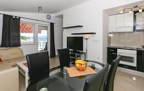 A modern living room with a sofa, a dining table with chairs, a TV, and a kitchen area with cabinets and appliances. - Gorgeous apartment in Jesenice (Jesenice)