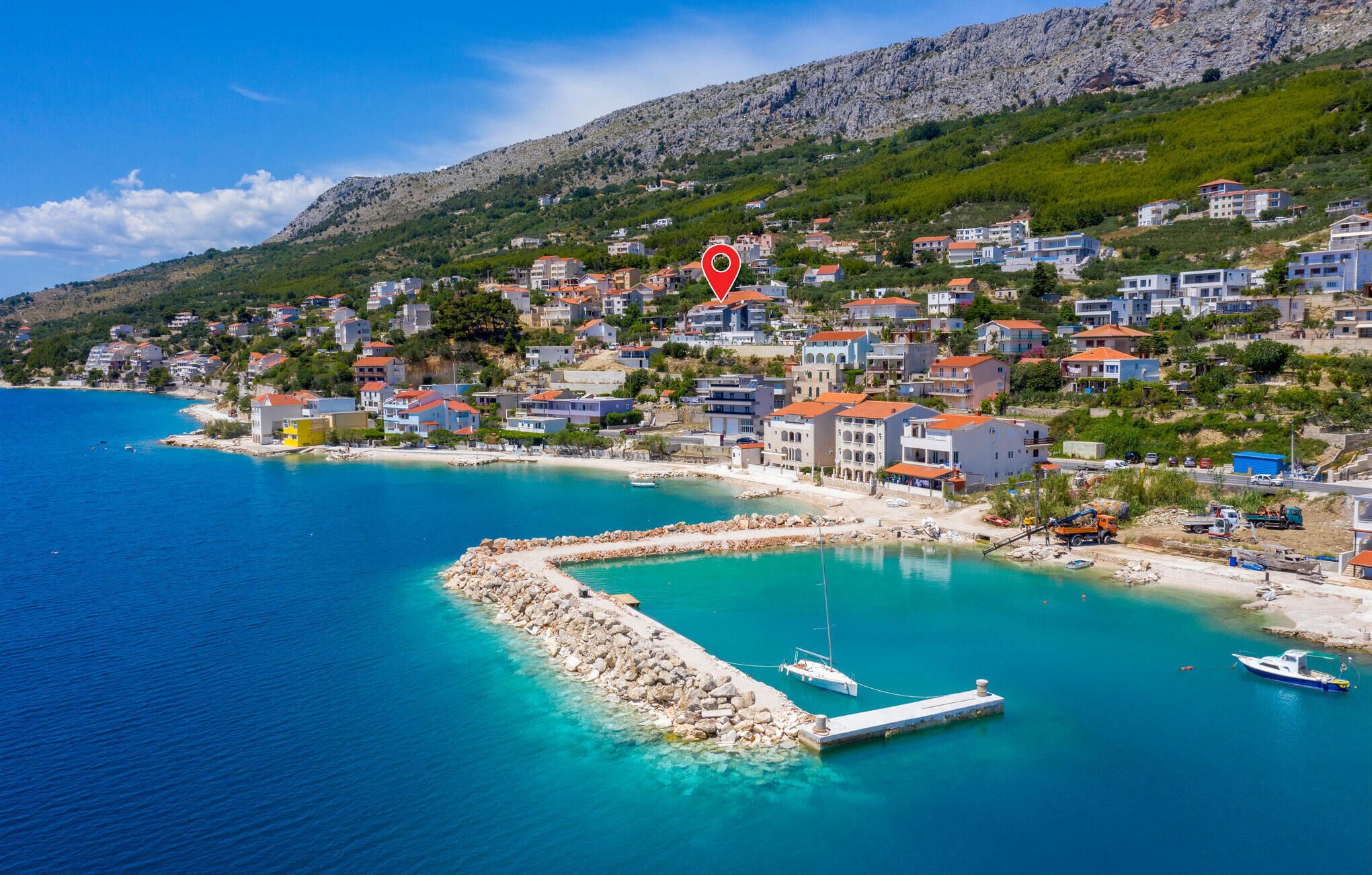 A coastal town with a rocky shoreline, a pier, and boats.