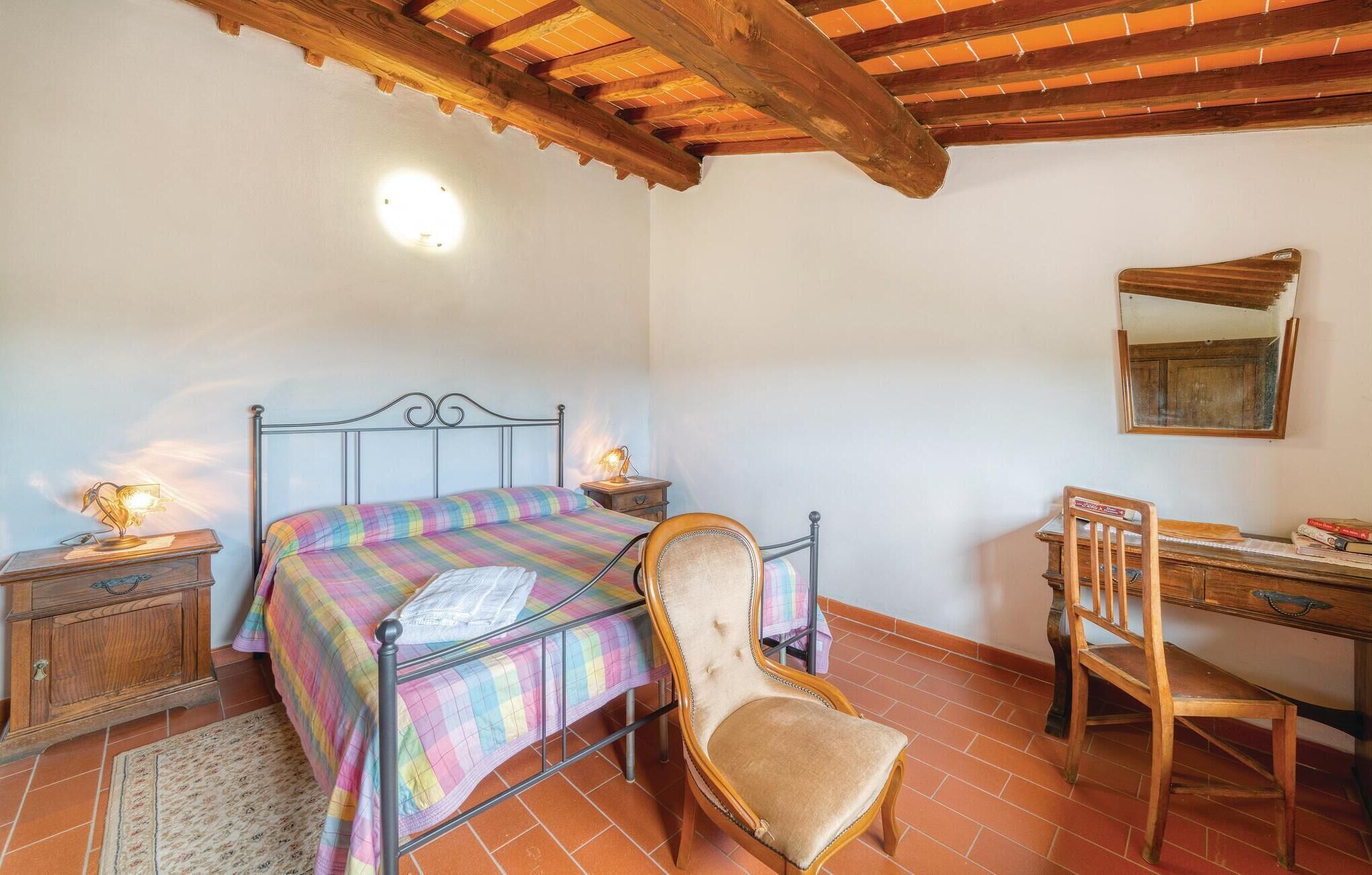 Ein Schlafzimmer mit Bett, Sessel, Schreibtisch und Spiegel.