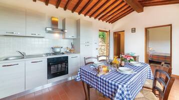 Una cucina con mobili bianchi, un fornello e un tavolo apparecchiato per mangiare.