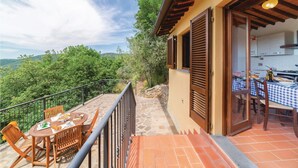 A balcony with a table set for dining, a kitchen area with a table set for a meal, and a view of the surrounding greenery. - Nice apartment in Loro Ciuffenna AR (Loro Ciuffenna AR)