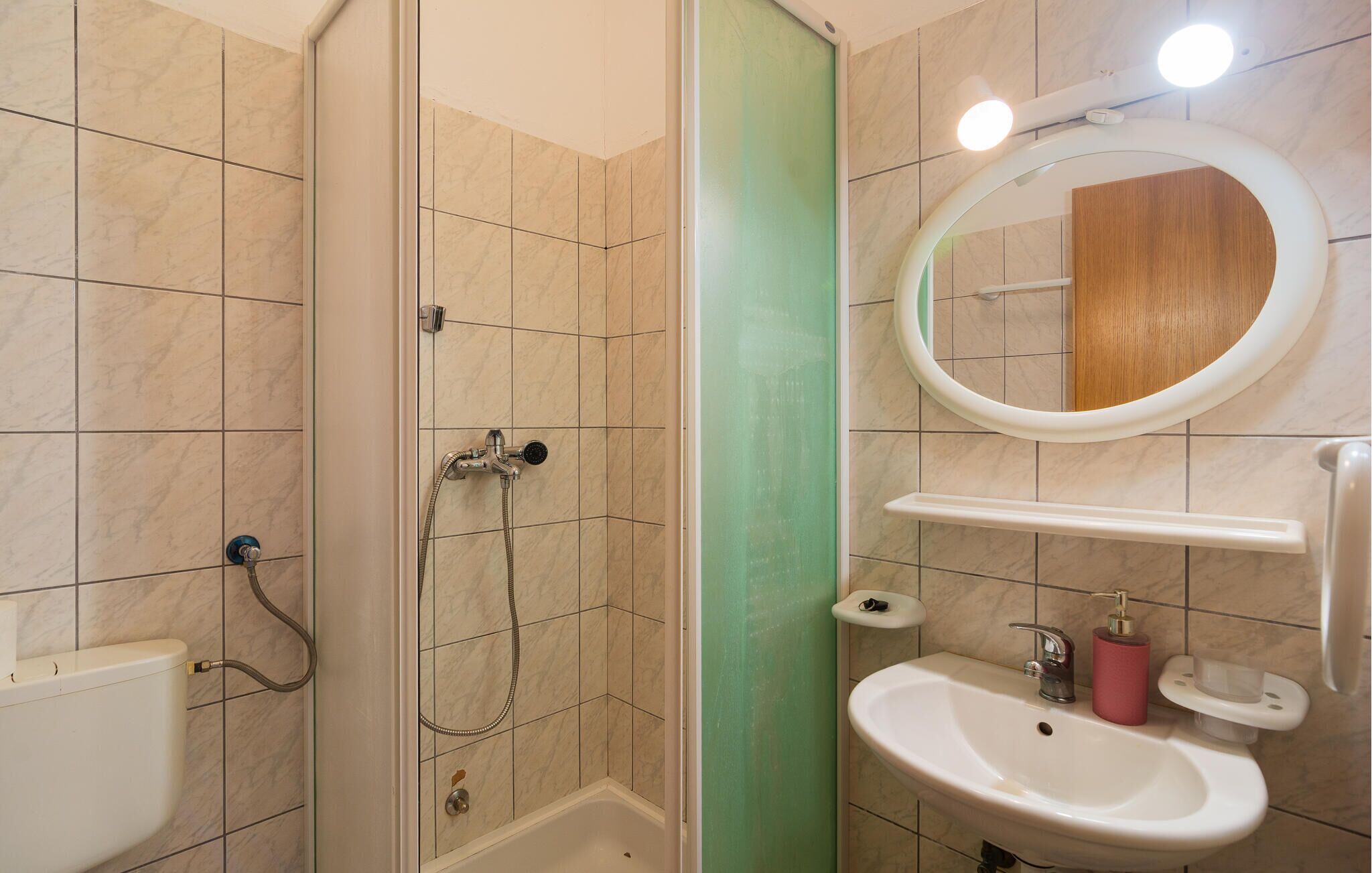 Ein Badezimmer mit Dusche, Toilette, Waschbecken und einem Spiegel.