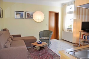 A living room with a sofa, a chair, a small table, a rug, a television, and a bookshelf.