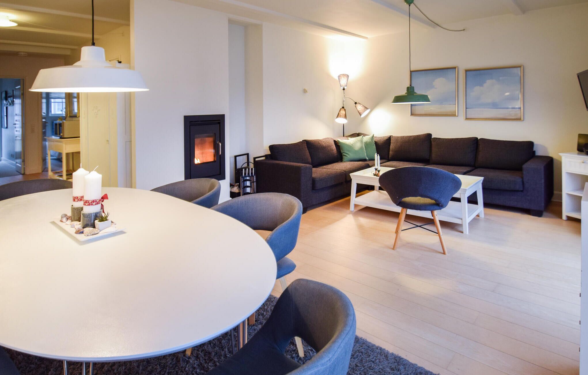 Een moderne woonkamer met een ronde eettafel, donkere banken en een open haard.
