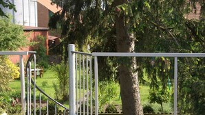 A wooden deck with a metal railing, a potted plant, and a tree in the background. - Studio with bicycles in the Schaumburg district (Meerbeck)