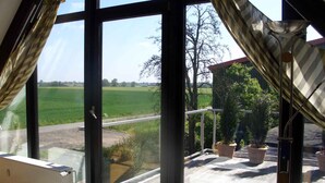 A room with large windows, a radiator, and a view of a green field and trees. - Studio with bicycles in the Schaumburg district (Meerbeck)