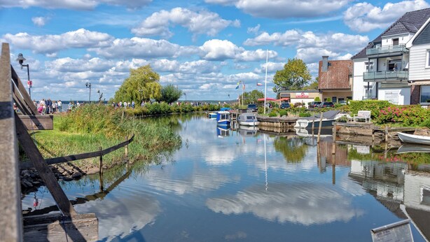 A calm river with boats, a wooden walkway, and buildings along the riverbank. - Studio with bicycles in the Schaumburg district (Meerbeck)