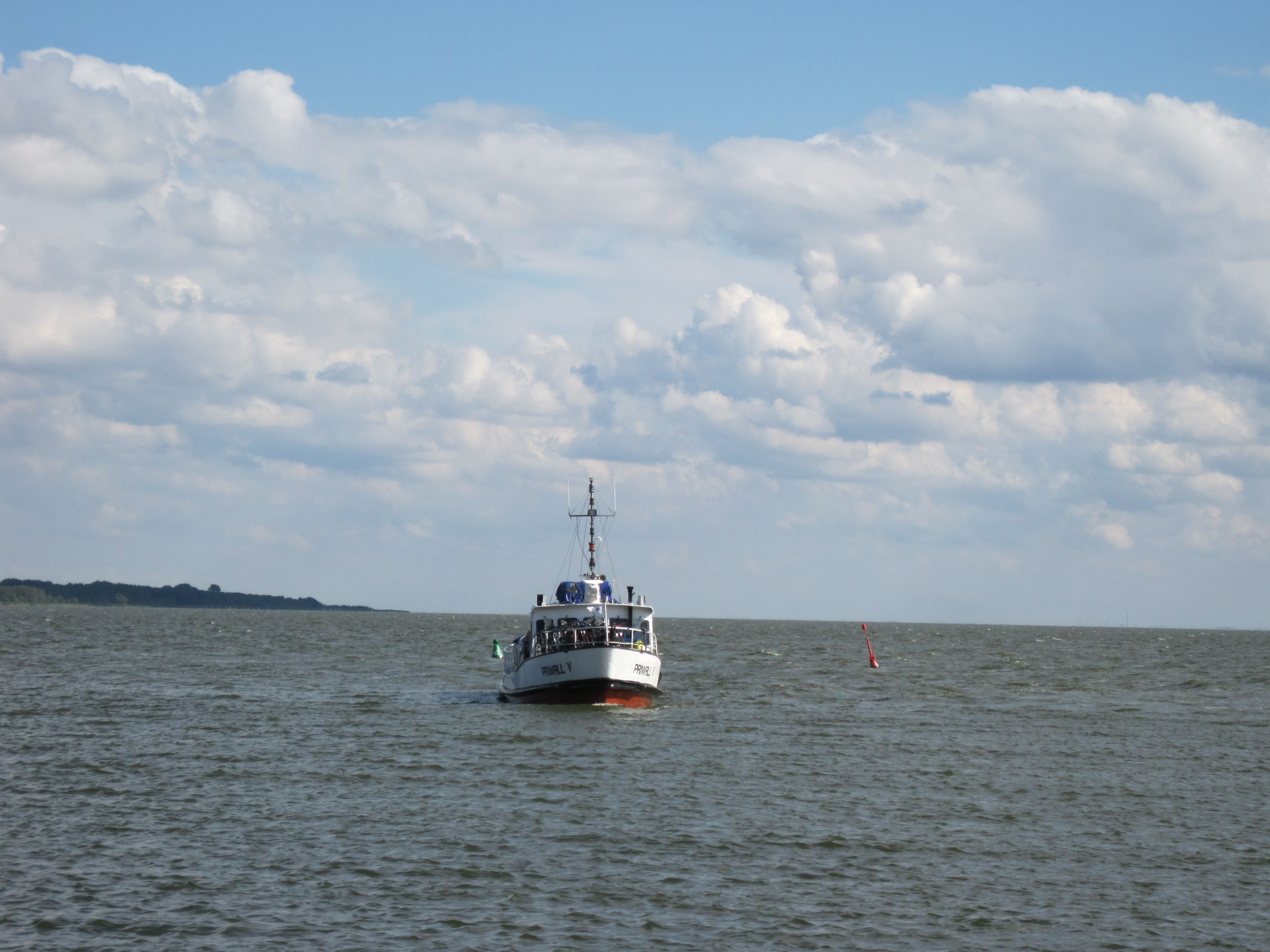 A boat on calm water with a partly cloudy sky.