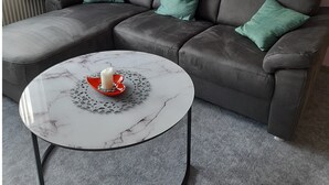 Ett modernt vardagsrum med en hörnsoffa, ett runt soffbord och konstverk på väggarna.