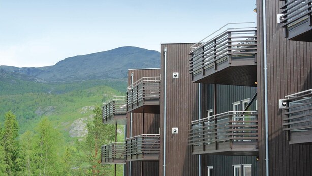 A modern multi-story building with balconies, set against a mountainous backdrop. - Pet friendly apartment in Hemsedal (Hemsedal)