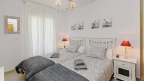 A bedroom with a double bed, two bedside tables with lamps, a mirror, and wall art. - Gorgeous apartment in Roldán with WiFi (Roldán)