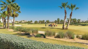 A golf course with palm trees, sand bunkers, and a clear blue sky. - Gorgeous apartment in Roldán with WiFi (Roldán)
