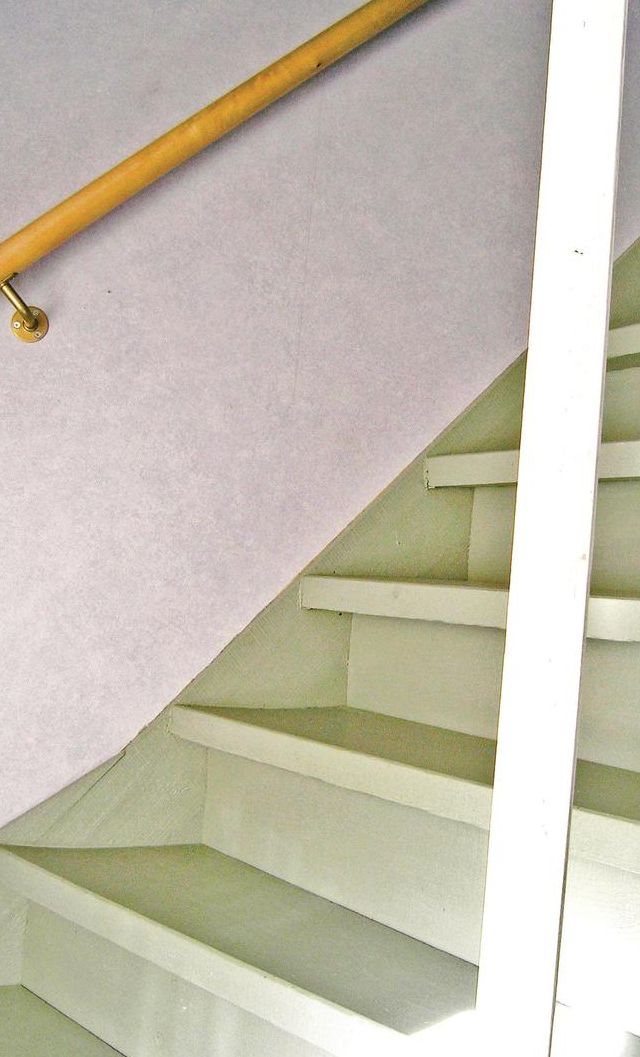 Una escalera con barandilla y pared blanca.