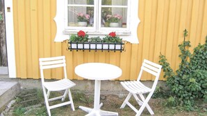 A yellow building with a white window and two white chairs around a small white table. - 1 bedroom awesome home in Strömsnäsbruk (Strömsnäsbruk)