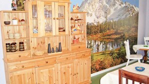 A wooden cabinet with glass doors, a dining table with chairs, and a mural of a mountain landscape. - 1 bedroom awesome home in Strömsnäsbruk (Strömsnäsbruk)