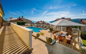A poolside area with a stone patio, lounge chairs, and a barbecue setup. - Amazing apartment in Rabac (Rabac)