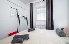 Ein Schlafzimmer mit einem Bett, einem Vorhangfenster, einem Heizkörper und einem an der Wand befestigten Handtuchhalter.
