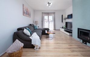 A modern living room with a sectional sofa, a flat-screen TV, and a wooden floor. - Amazing apartment in Rabac (Rabac)
